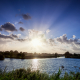 Zonnestralen vanachter de wolken vandaan over het water in Schipsloot Roderwolde Drenthe