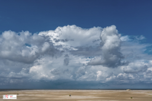 Enorme wolkenlucht en 2 mensen op een verlaten strand