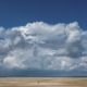 Enorme wolkenlucht en 2 mensen op een verlaten strand