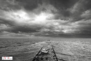 Golfbreker met imposante lucht Vlieland in zwart-wit