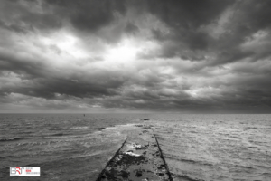 Golfbreker met imposante lucht Vlieland in zwart-wit