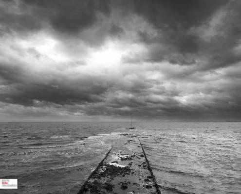 Golfbreker met imposante lucht Vlieland in zwart-wit